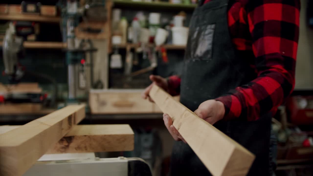 tomado de cerca. el maestro corta a un trabajador de madera toma una tabla de madera e la inserta en la máquina en madera. cámara lenta.