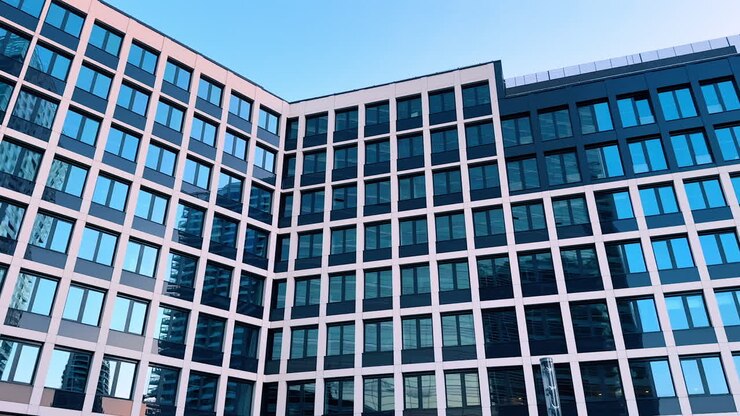 Bratislava, Slovacchia - 5 giugno 2025: Edificio urbano con finestre in vetro. Le finestre riflettenti di un edificio contemporaneo catturano le strutture vicine sotto un cielo azzurro e limpido in un contesto urbano.