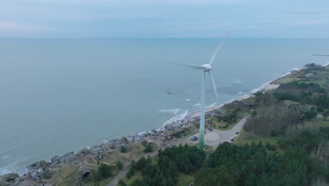 estableciendo una vista aérea de los edificios fortificados abandonados a la orilla del mar en los fuertes del norte de karosta en la playa del mar báltico en liepaja, día nublado, turbina eólica, disparo de avión no tripulado hacia adelante