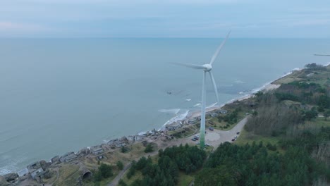 establishing aerial view of abandoned seaside fortification buildings at karosta northern forts on the beach of baltic sea in liepaja, overcast day, wind turbine, drone shot moving forward