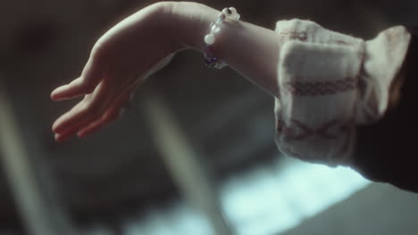a hand adorned with a bracelet and ring reaches out in soft focus