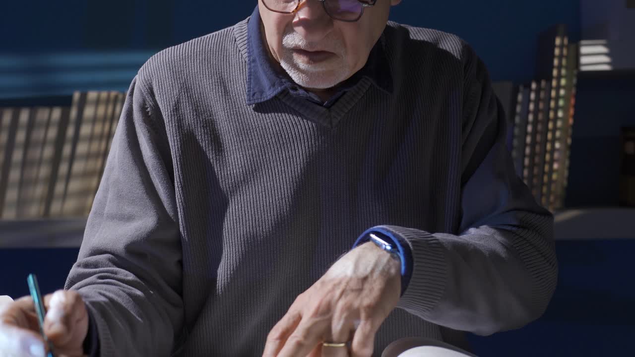 그 노인은 그의 연구실에서 그의 연구에 대한 역사적이고 과학적인 책을 읽고 있습니다.