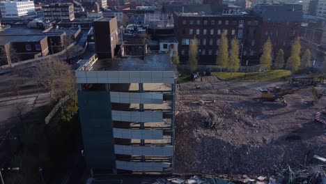 Demolished-multi-storey-car-park-wreckage-debris-in-town-regeneration-aerial-view-demolition-site-orbit-right