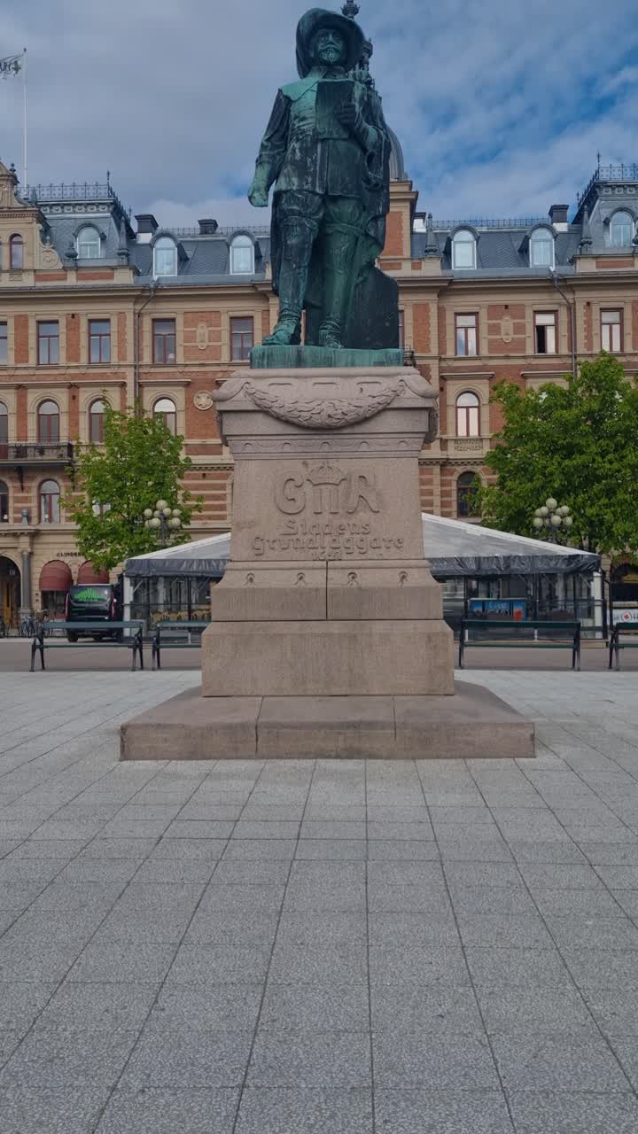 Revealing shot of the Gustav II Adolf statue in front of Hirschska huset at the Stora Torget central square in Sundsvall, Sweden under a cloudy sky