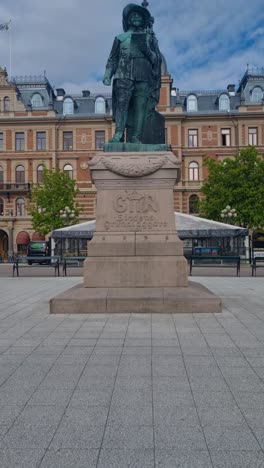 revealing shot of the gustav ii adolf statue in front of hirschska huset at the stora torget central square in sundsvall, sweden under a cloudy sky