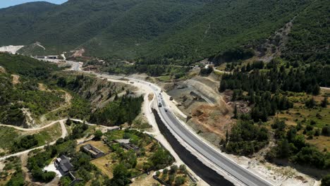 excavators dig into the foothills near a main road, showcasing heavy machinery at work on a large-scale construction and land development project