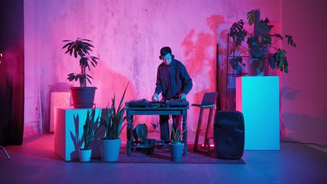 modern dj of asian appearance performs a music track in neon lighting.