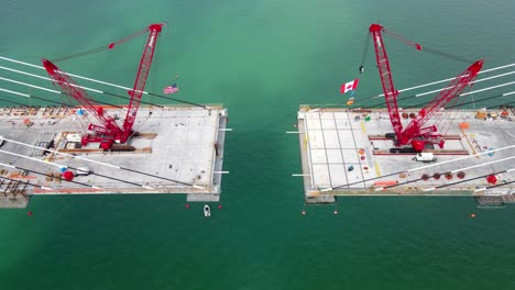 construction of gordie howe international bridge with cranes over detroit river, aerial flyover