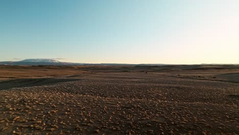 high aerial panoramic establishing approach of an suv driving across the moab desert at sunset, glowing golden terrain
