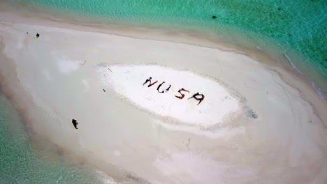 menschen bilden auf einer winzigen sandinsel in raja ampat die buchstaben nusa, was in der indonesischen sprache insel bedeutet, luftaufnahme eines dolly-outs