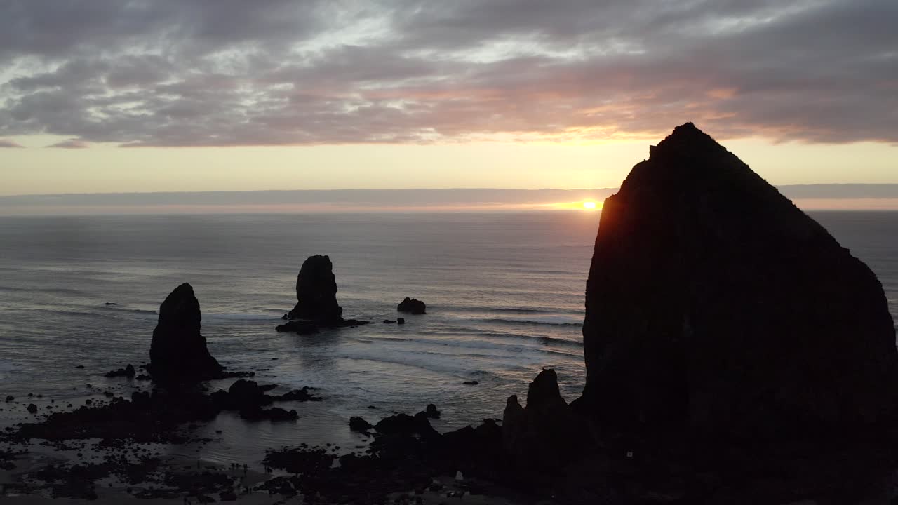 aéreo, roca de pajar en cannon beach, oregón, puesta de sol de rocas de silueta sobre el océano