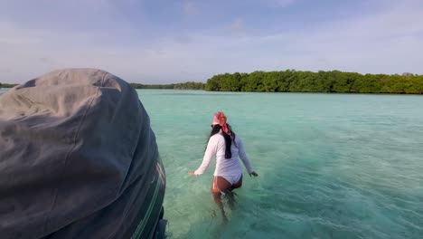 woman-gets-off-the-boat-to-go-swimming-inside-turquoise-shallow-water,-caribbean-sea