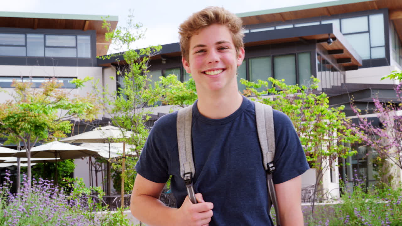 대학 건물 밖의 남성 고등학교 학생의 초상화가 느린 동작으로 촬영되었습니다.