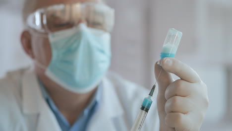 Close-up-shot-of-unrecognizable-nurse-or-doctor-in-gloves-filling-syringe-from-ampule-with-covid-19-vaccine.-Nurse-filling-injection-syringe-from-vial.-High-quality-4k-footage