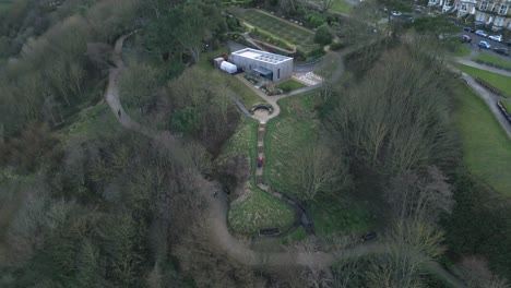 Toma-Aérea-Hacia-Atrás-De-Una-Casa-Situada-Entre-Densos-árboles-Y-Un-Pequeño-Sendero-En-La-Bahía-De-Scarborough,-Inglaterra