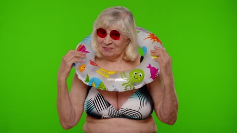 Elderly-woman-tourist-in-swimsuit-dancing,-celebrating,-smiling-with-rubber-ring-on-chroma-key