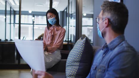 diversos colegas de oficina masculinos y femeninos con máscaras faciales discutiendo en una oficina moderna