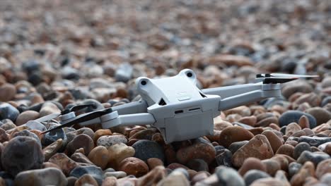 a-gray-drone-lays-on-the-pebbles-of-a-beach,-brighton,-sussex,-england