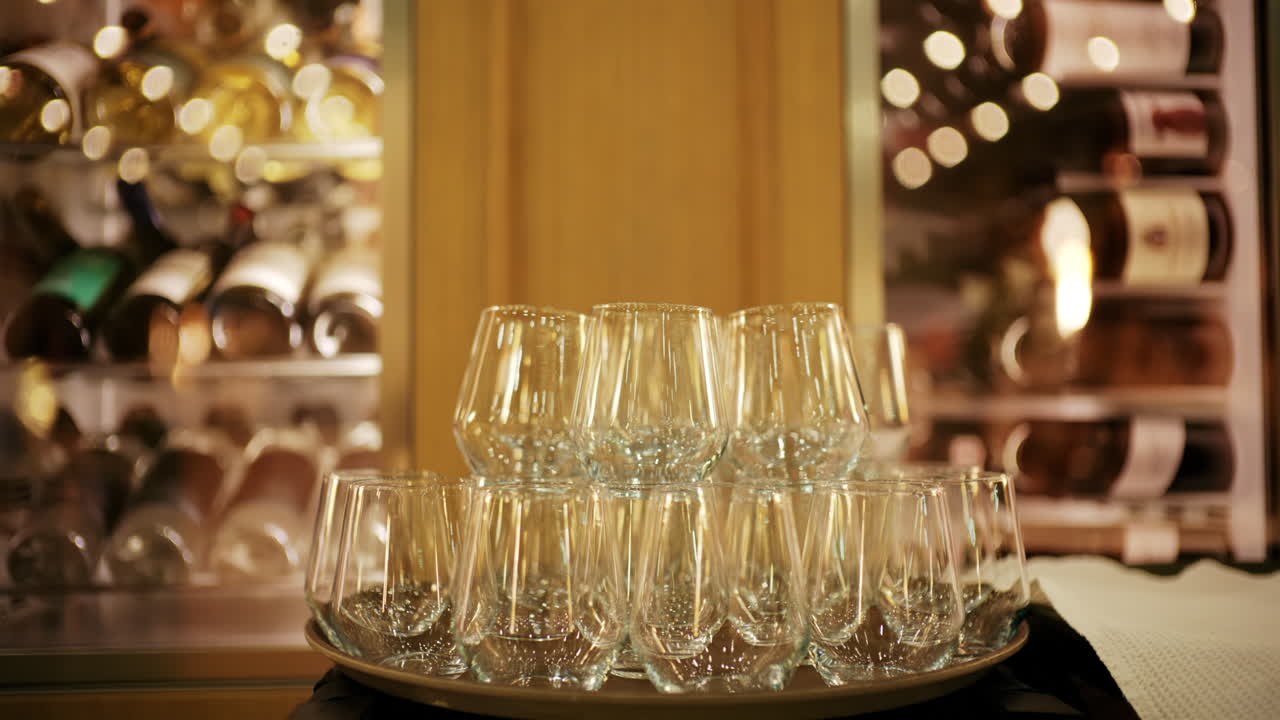 Taças de vinho elegantes dispostas em uma bandeja em um ambiente de restaurante com iluminação suave, com adegas desfocadas ao fundo.