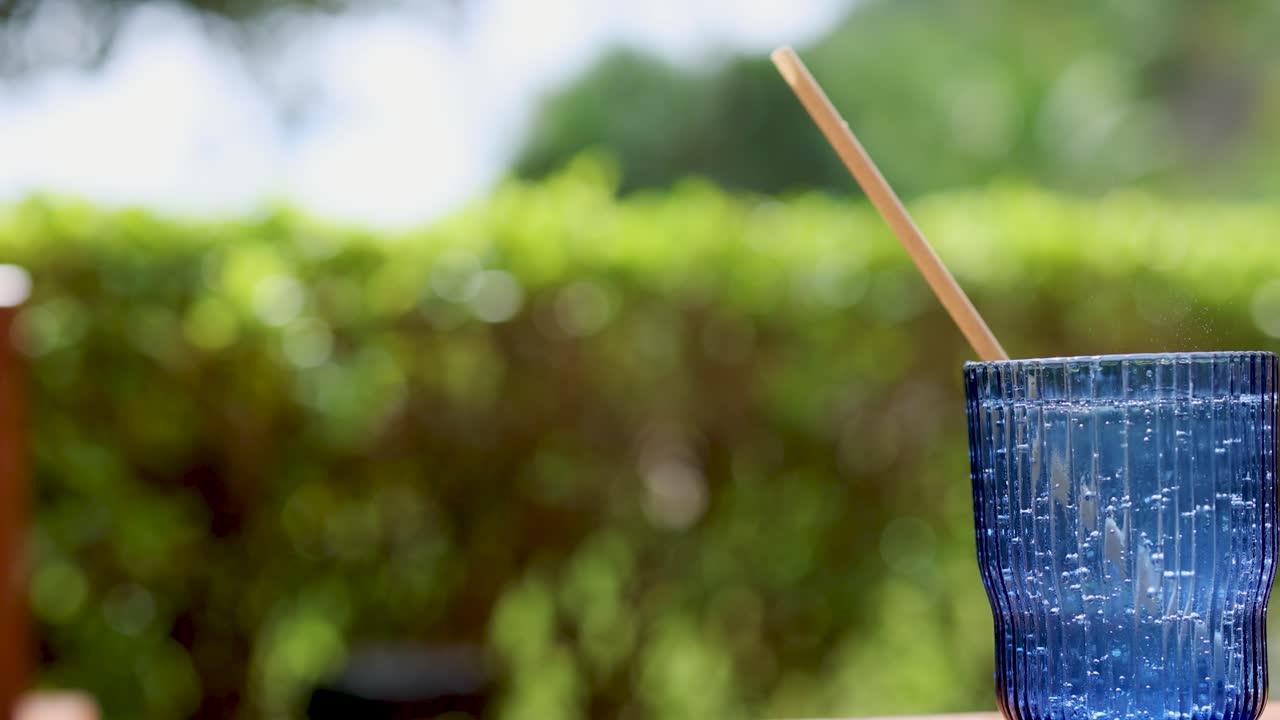 흐릿한 초록색 배경과 함께 야외에서 반이는 물 한 잔