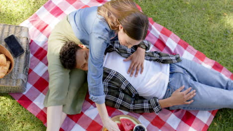 una pareja feliz y diversa tiene un picnic en un jardín soleado, en cámara lenta.