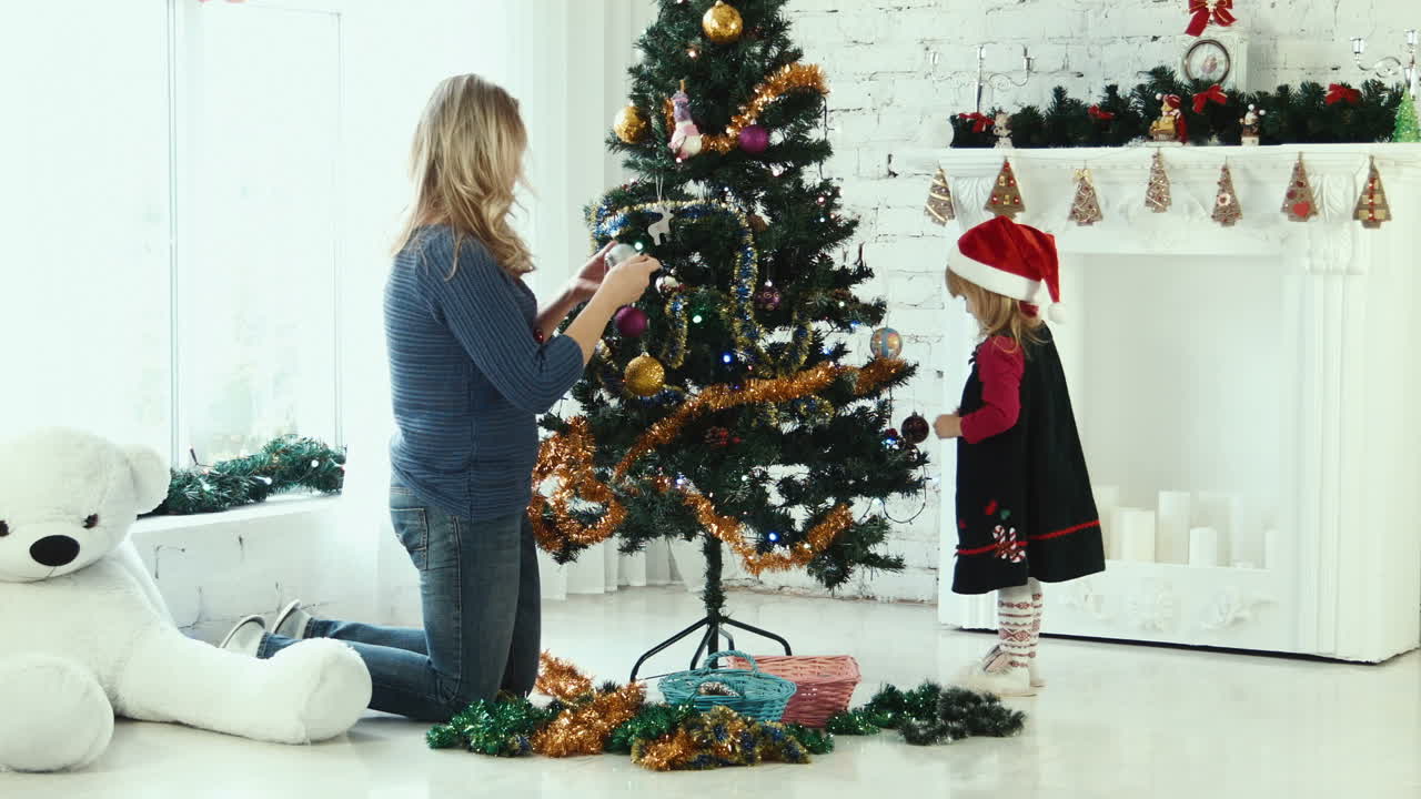 어머니 와 딸 이 크리스마스 트리 를 장식 하고 있다