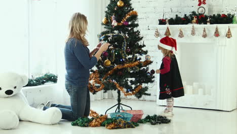 mother and daughter decorating christmas tree