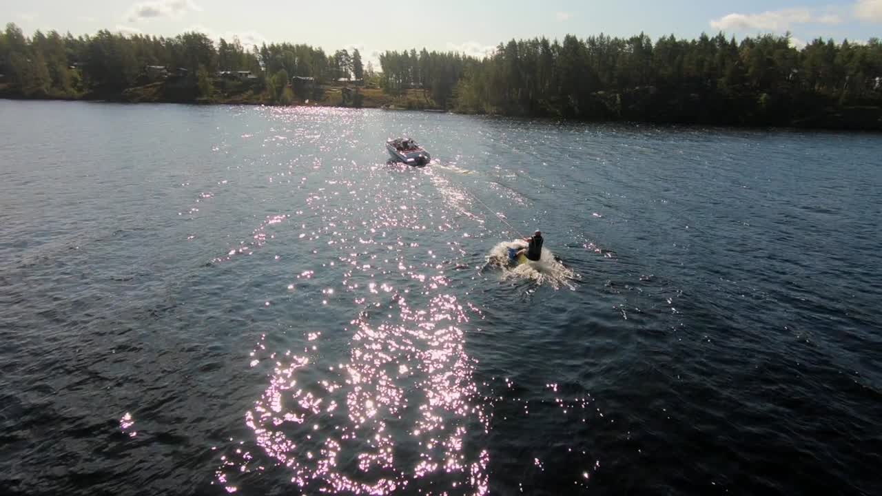 cámara lenta de un dron volando sobre un joven montando un wakeboard después de un bote deportivo en el archipiélago sueco en el verano sub5