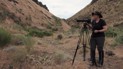 sagebrush coulee: fotógrafa mujer ajusta la cámara de lente grande en un trípode