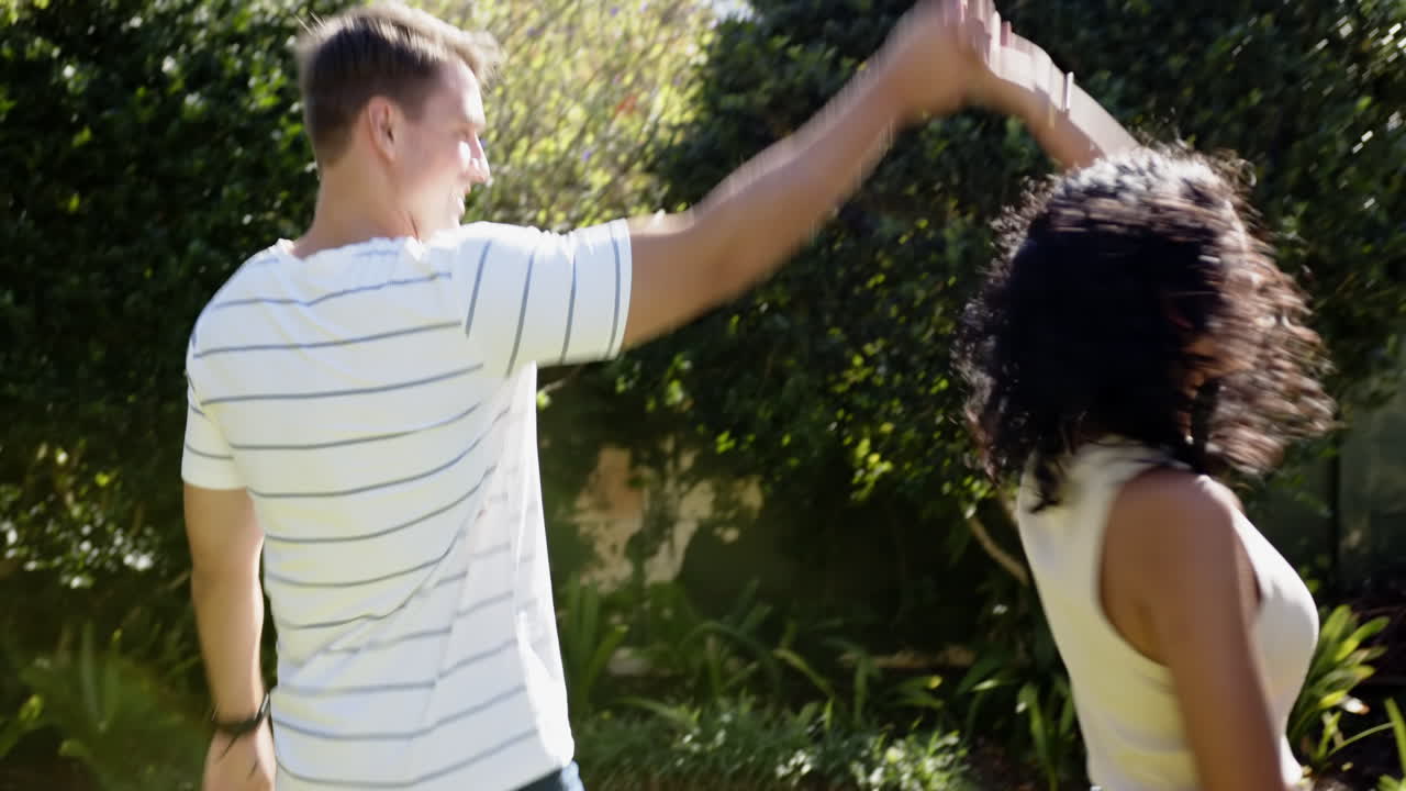 Walking together in garden, young multiracial couple enjoying sunny day outdoors, copy space