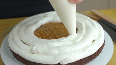 close up of woman hands making sweet cake with white cream and biscuit.