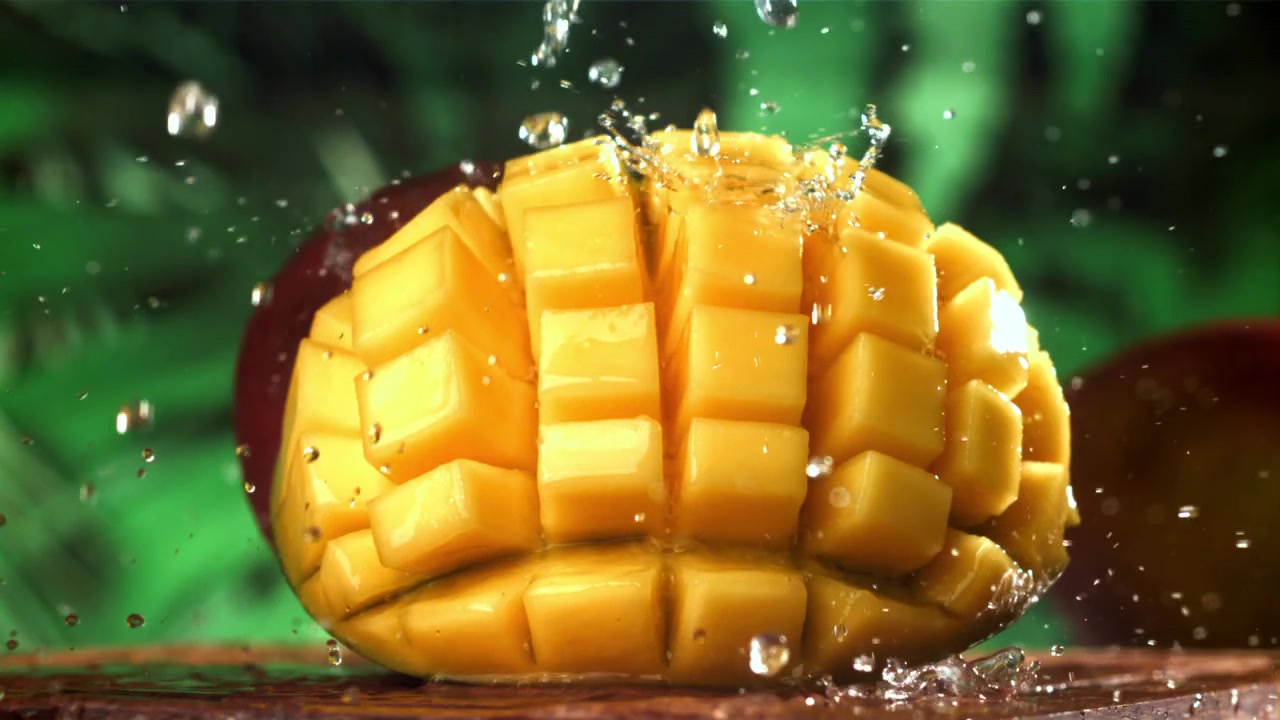 Acqua che schizza al rallentatore su cubetti di mango appena tagliati