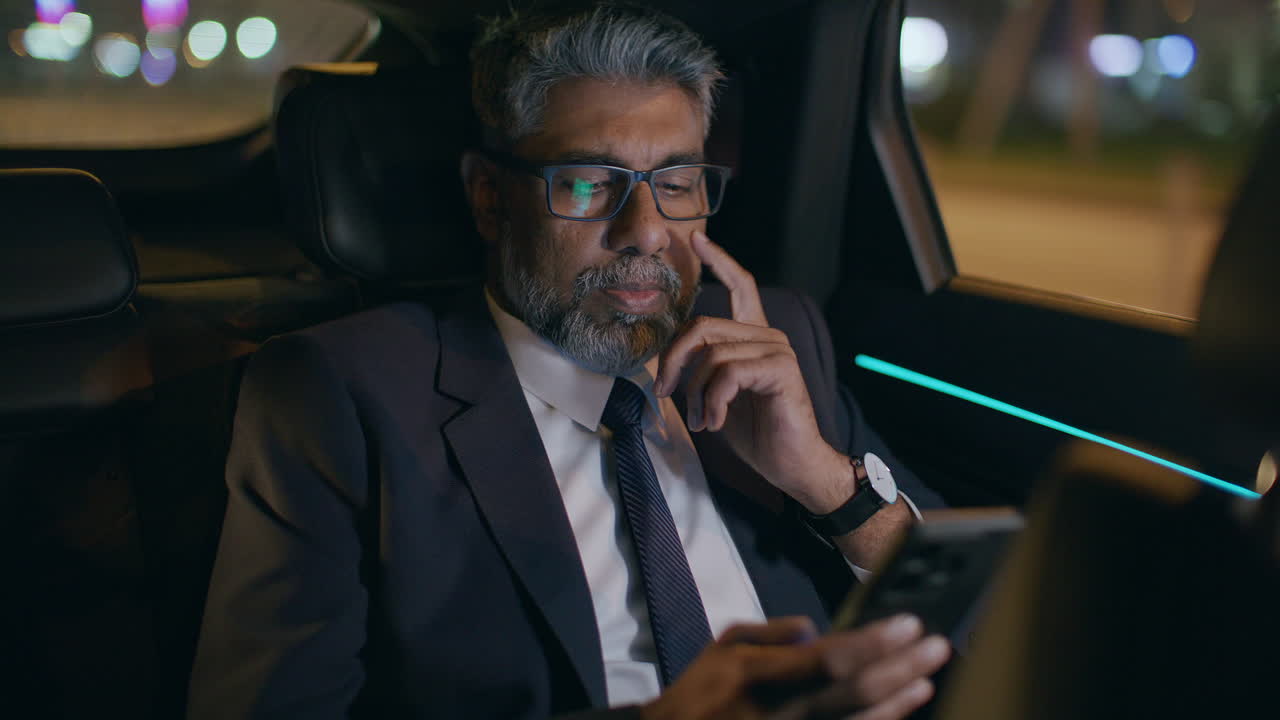 Senior Businessman Using Smartphone while Riding in Car at Night