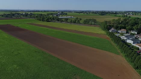 Una-Vista-Aérea-De-Un-Trabajo-De-Parches-De-Tierras-De-Cultivo-Junto-A-Un-Parque-De-Casas-Móviles-En-Un-Día-Soleado