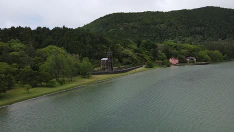 Aerial-view-of-the-Chapel-of-Nossa-Senhora-das-VitÃ³rias,-a-small-funerary-chapel-on-the-southwestern-corner-of-Lagoa-das-Furnas-in-the-civil-parish-of-Furnas-on-the-Azorean-island-of-SÃ£o-Miguel-1