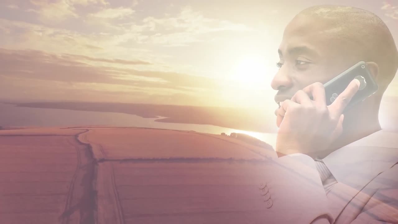 Animation of smiling african american man using smartphone over sunset landscape