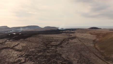 desierto de roca volcánica desolada con respiraderos humeantes y volcán