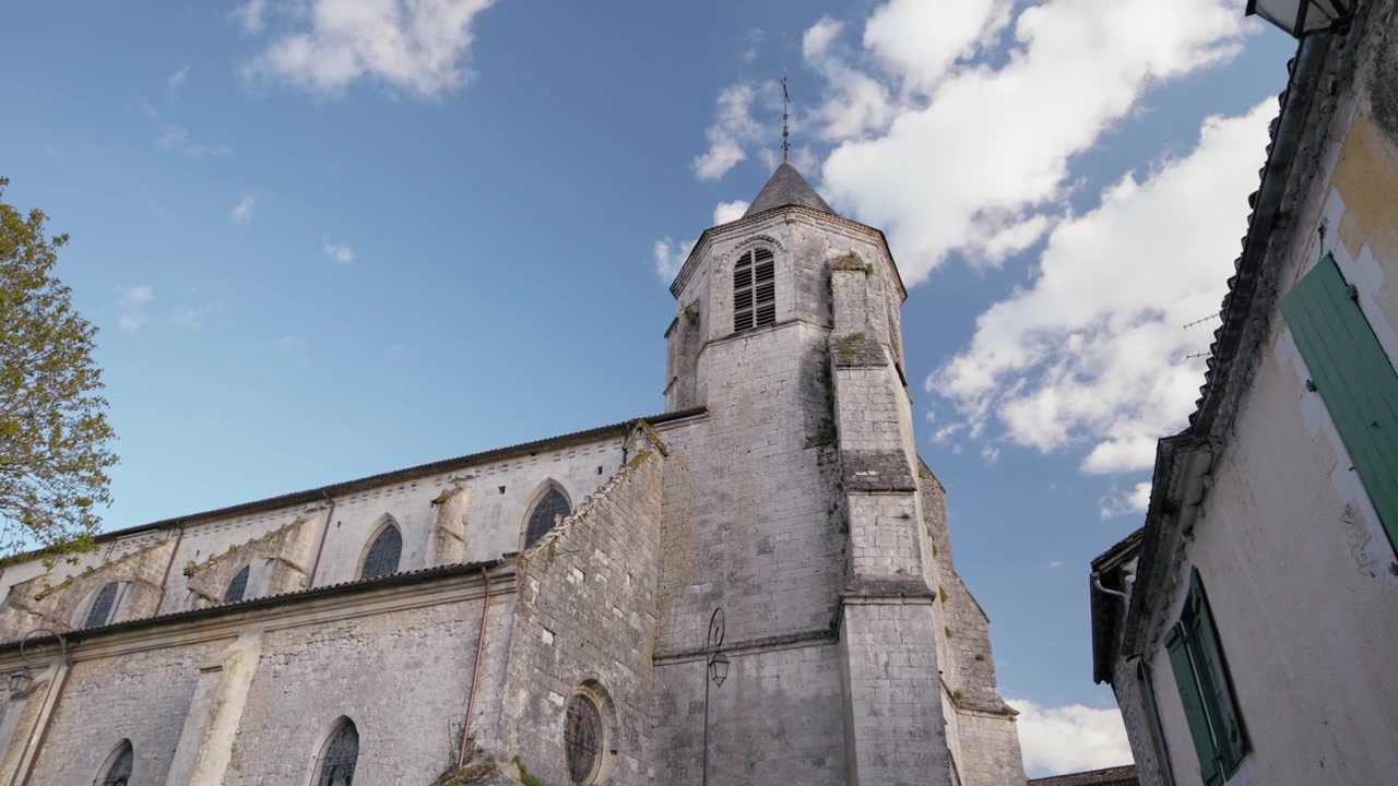O campanário da igreja de Saint-Félicien eleva-se acima das casas medievais da vila de Issigeac. Património arquitetónico do Perigord. Plano de acompanhamento lateral em câmara lenta