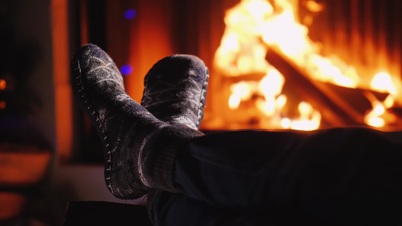 저녁에 불이 타오르는 벽난로 근처의 양말 신은 다리