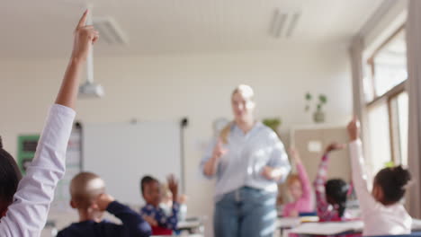 in school classroom, students raising hands while female teacher engaging with them