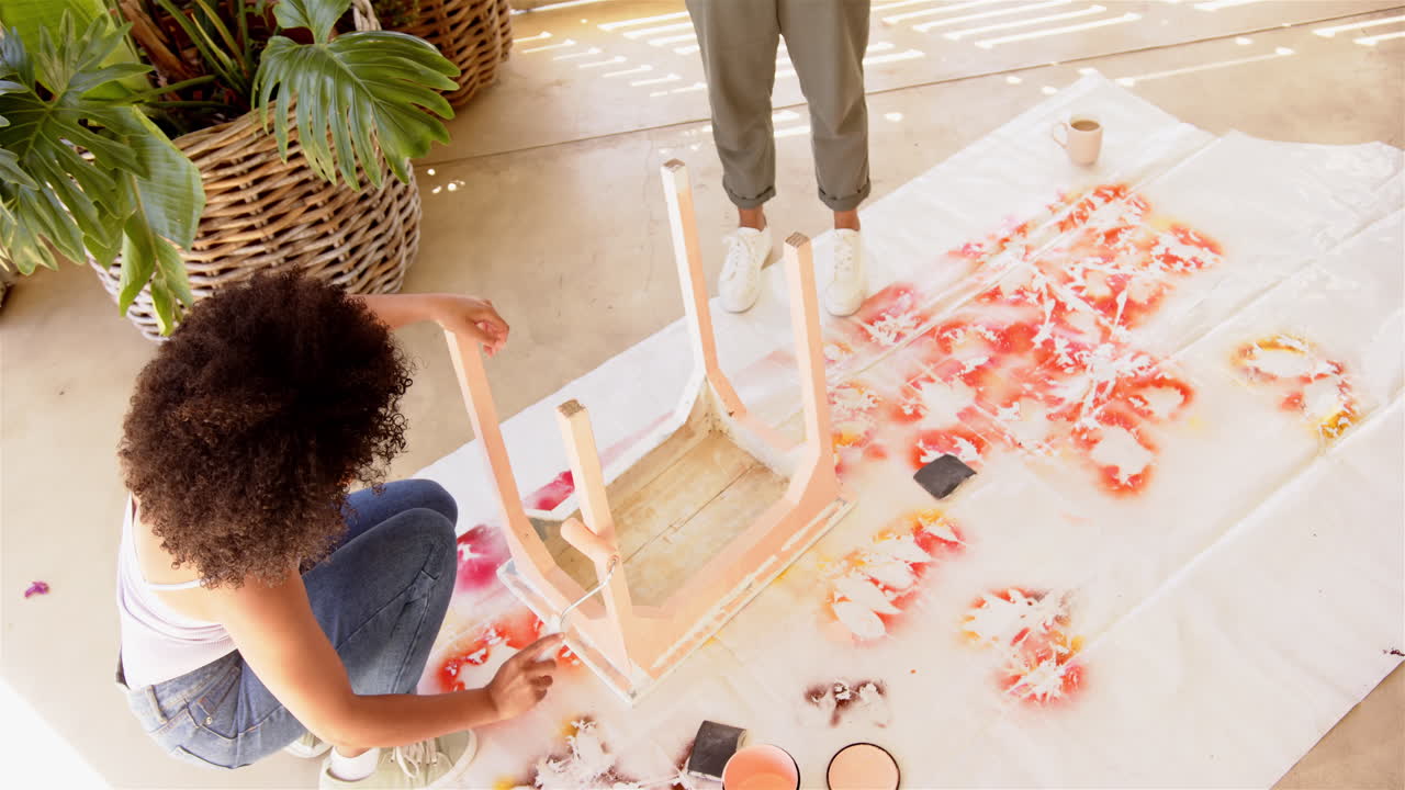 Painting wooden chair, woman and man working on DIY home project