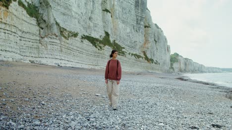 woman hiking on a rocky beach by cliffs