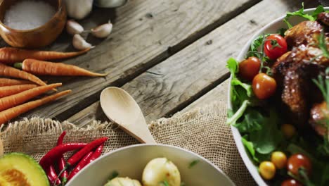 close up view of cooked chicken and multiple food ingredients on wooden surface