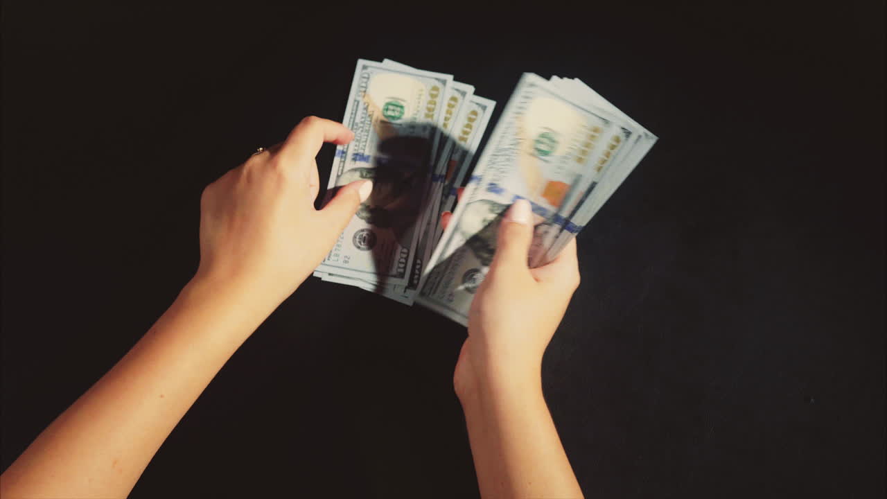 Hands Counting Stacks of US Dollars