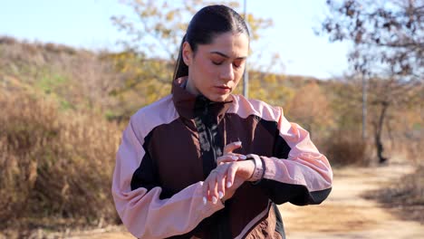 mujer deportiva comprobando el reloj inteligente en una parada de carrera