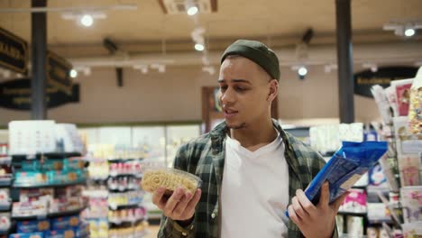 a guy chooses products in the grocery store, thinking between cooked and raw pasta