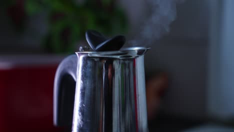 close up of a shiny and reflecting coffe machine that is brewing coffe, steam rising up