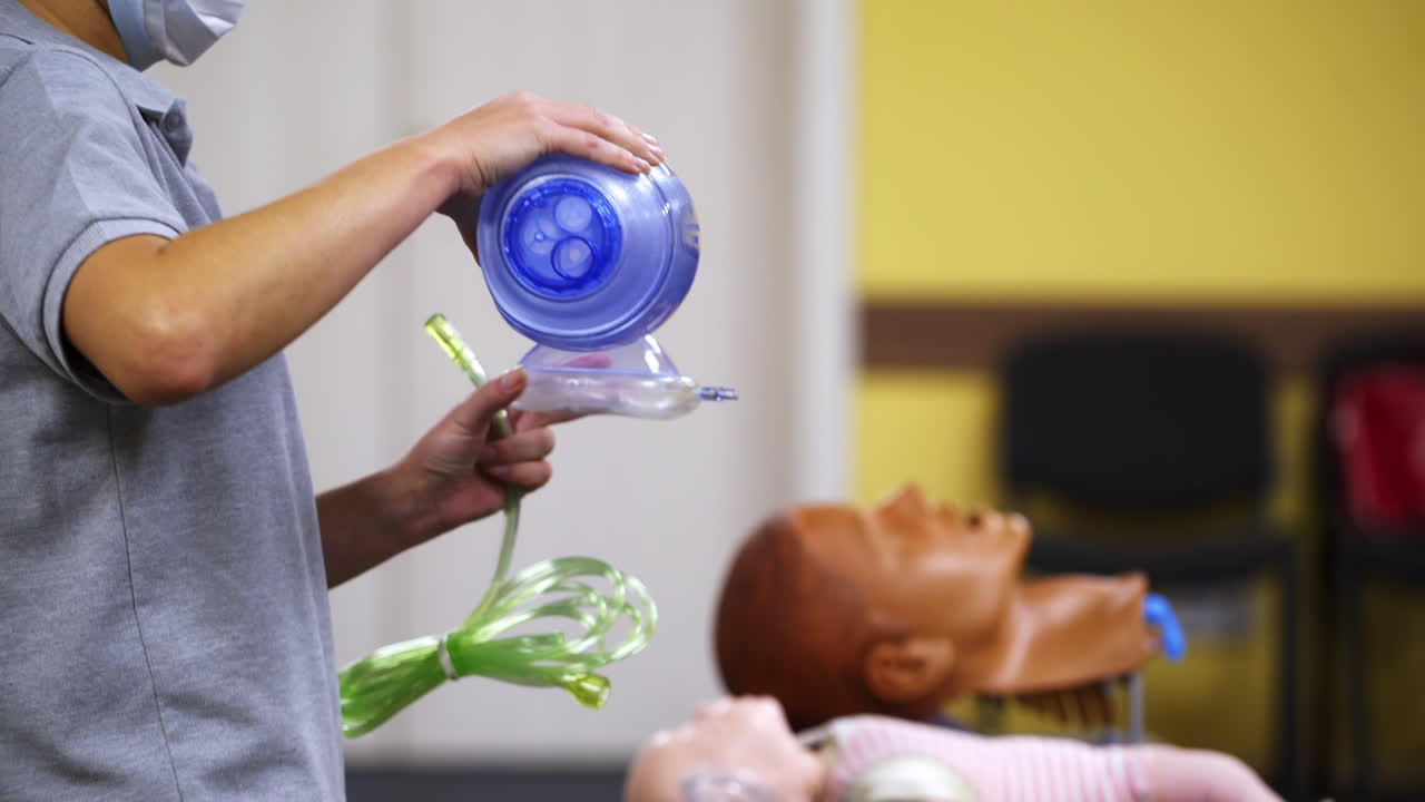 Medic is using CPR technique on dummy in first aid class. Oxigen mask on medical doll demonstration. Training video courses.