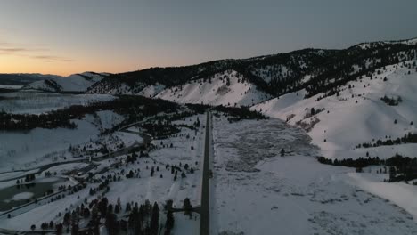 Fly-Over-Asphalt-Road-Passing-Through-Snow-Covered-Mountains-Near-Sun-Valley,-Idaho