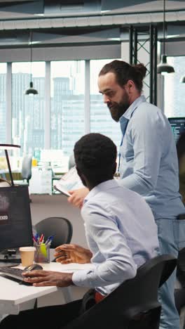 vertical video programmer in office requesting help from coworkers to fix critical error